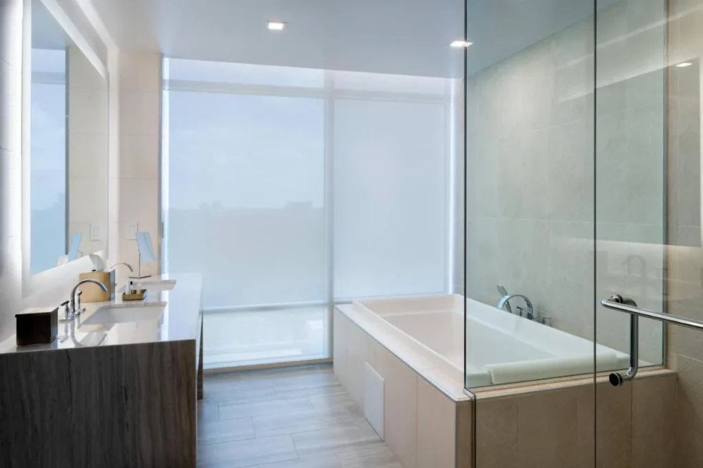 Bathroom with double vanity and a soaking tub behind glass at JW Marriott Orlando Bonnet Creek