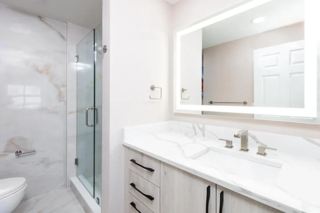 Bathroom with glass walk-in shower, marble-look tile and lighted mirror at Westgate Palace