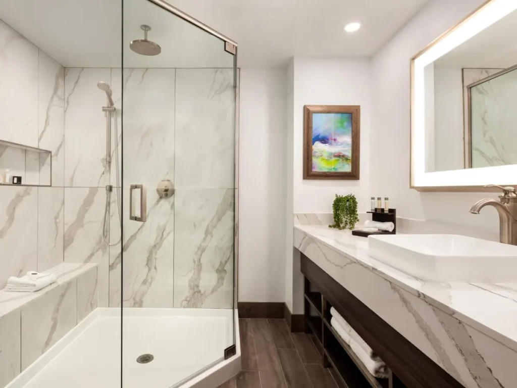 Cuarto de baño con ducha de cristal, cabezal de ducha de lluvia y tocador de mármol en Buena Vista Suites