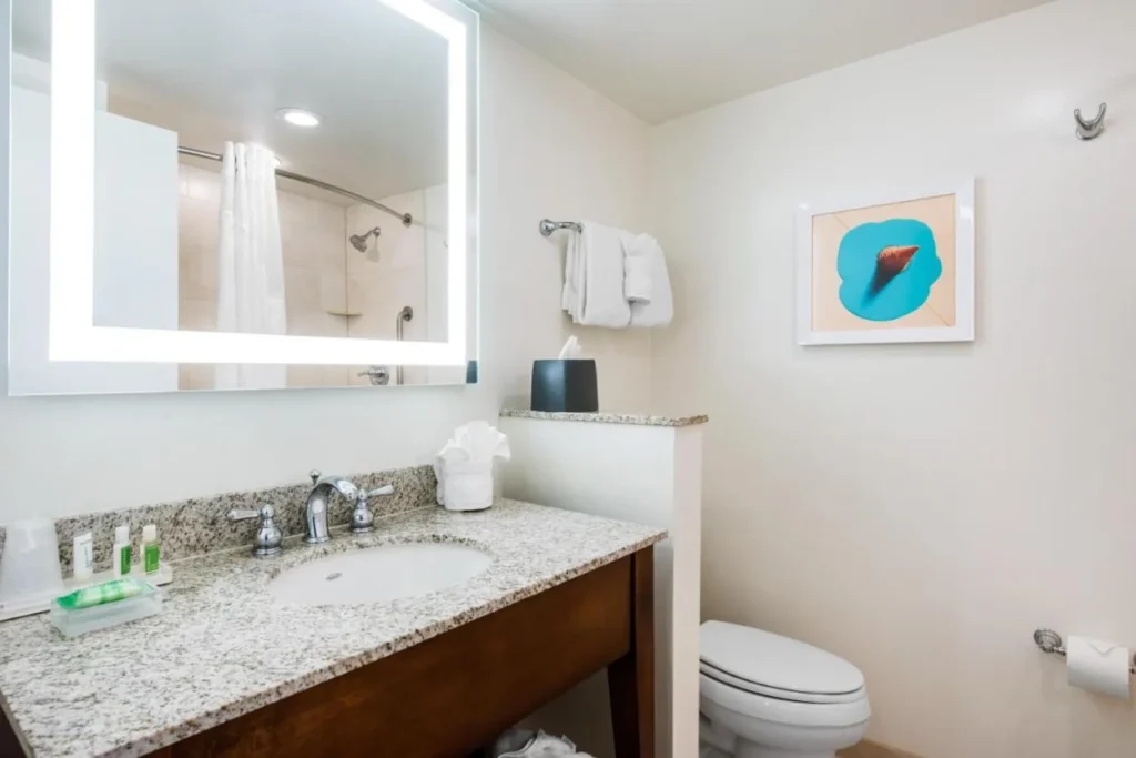 Cuarto de baño con tocador de granito y espejo iluminado en Holiday Inn Orlando Disney Springs