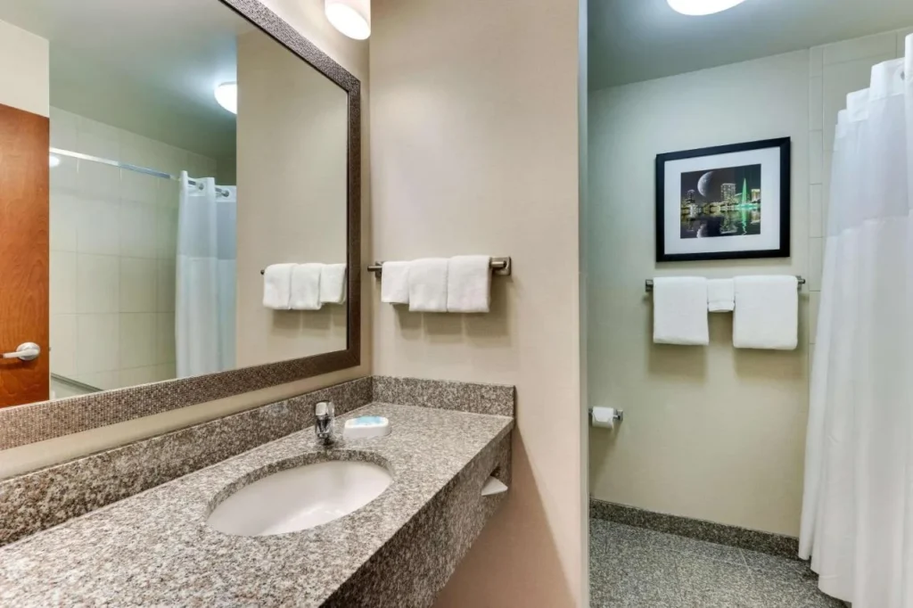 Bathroom with granite vanity, mirror, towels and shower curtain at Drury Inn & Suites near Universal