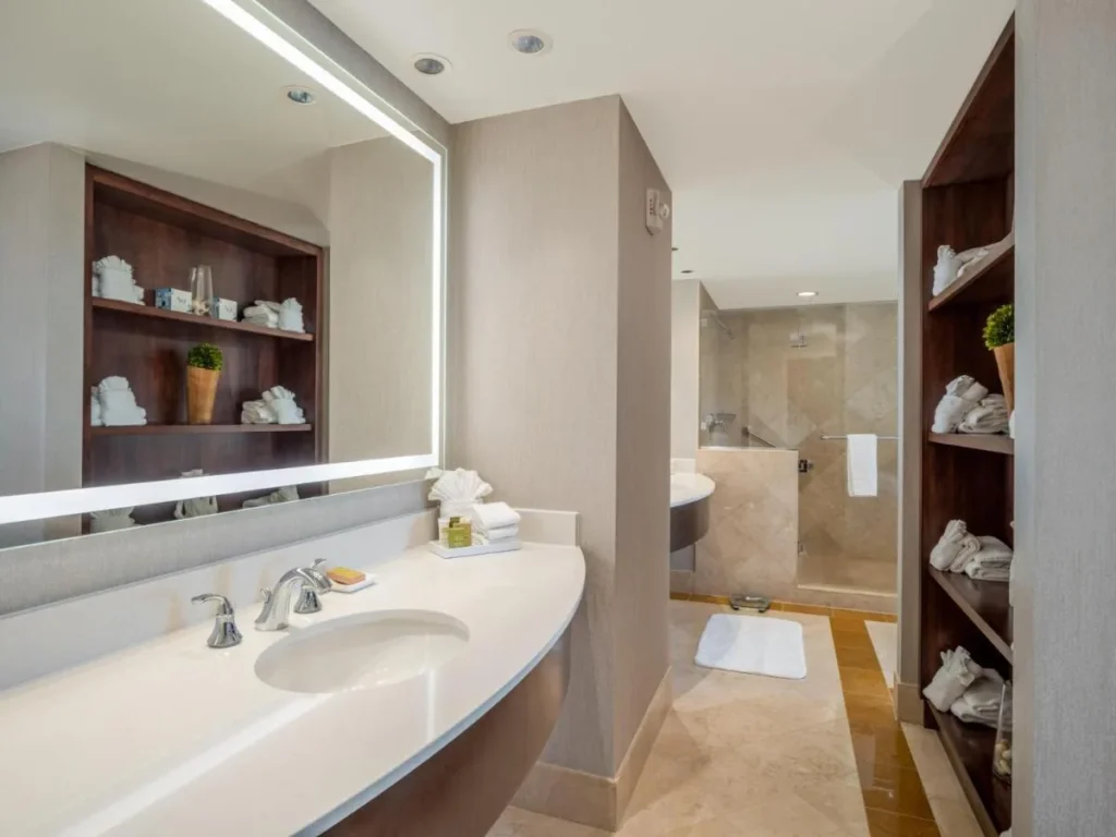 Bathroom with lit mirror, curved vanity and glass shower at Signia by Hilton Orlando Bonnet Creek