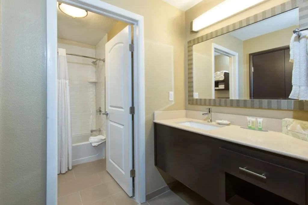 Cuarto de baño con tocador largo y bañera con ducha en Staybridge Suites Orlando at SeaWorld