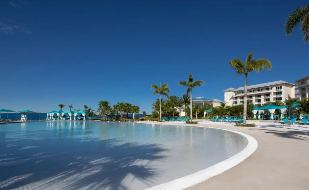 Beach-entry lagoon pool with palm trees, cabanas and a hotel wing at Margaritaville Resort Orlando