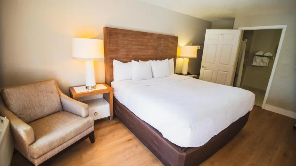 Bed with wood headboard, armchair and bedside lamps at Quality Inn and Suites By the Parks