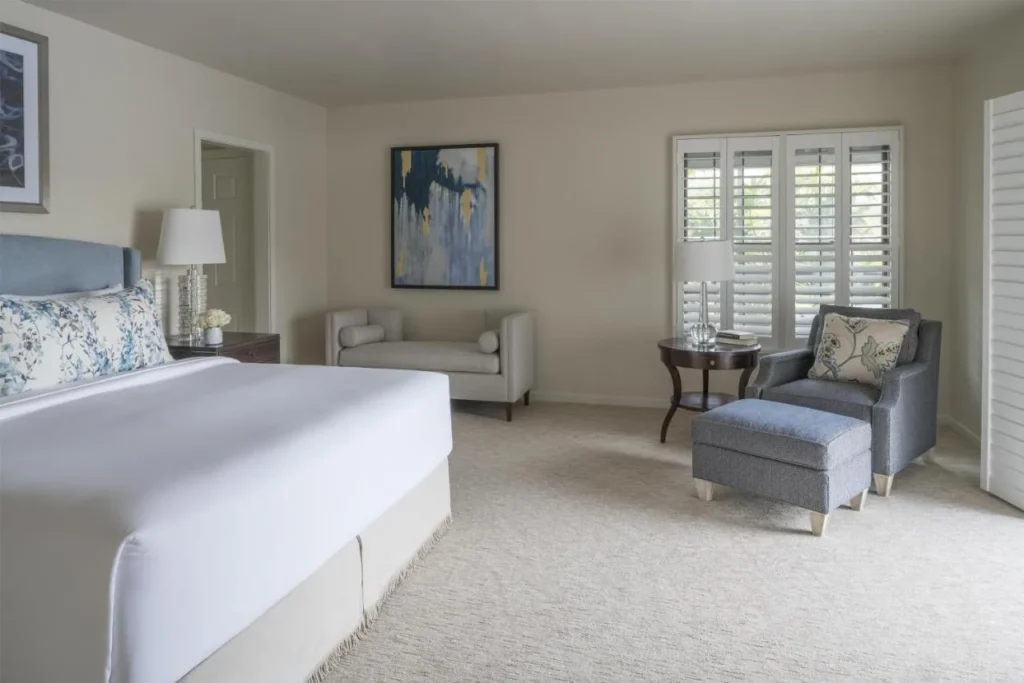 Dormitorio en Hyatt Regency Grand Cypress con cama king, sillón, otomana, banco y ventanas cerradas