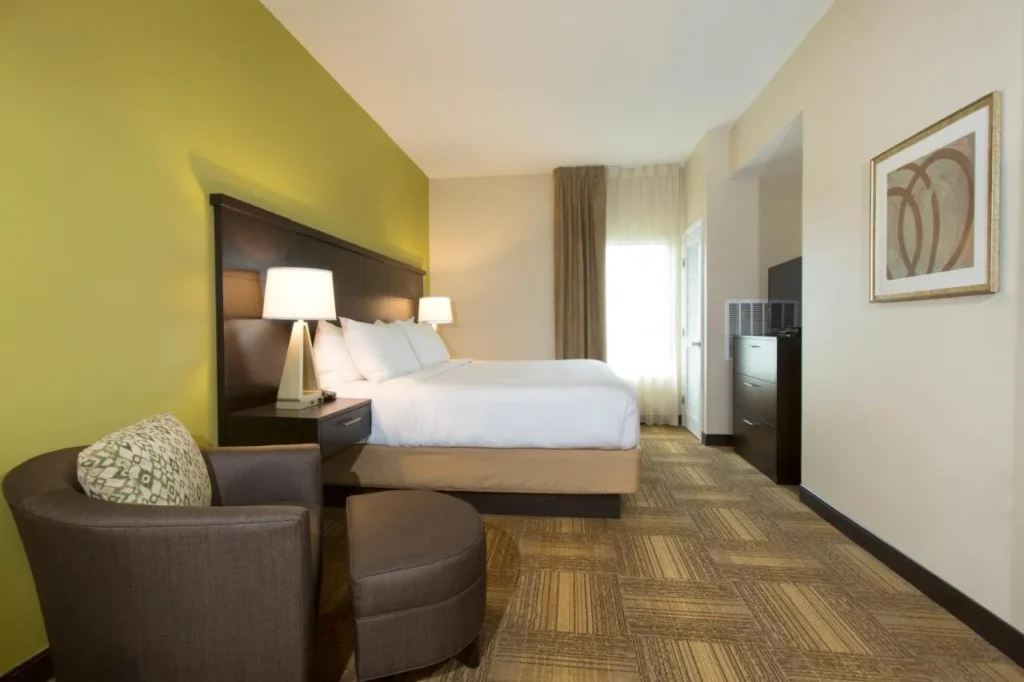 Habitación con cama king size, sillón y otomana en Staybridge Suites Orlando at SeaWorld