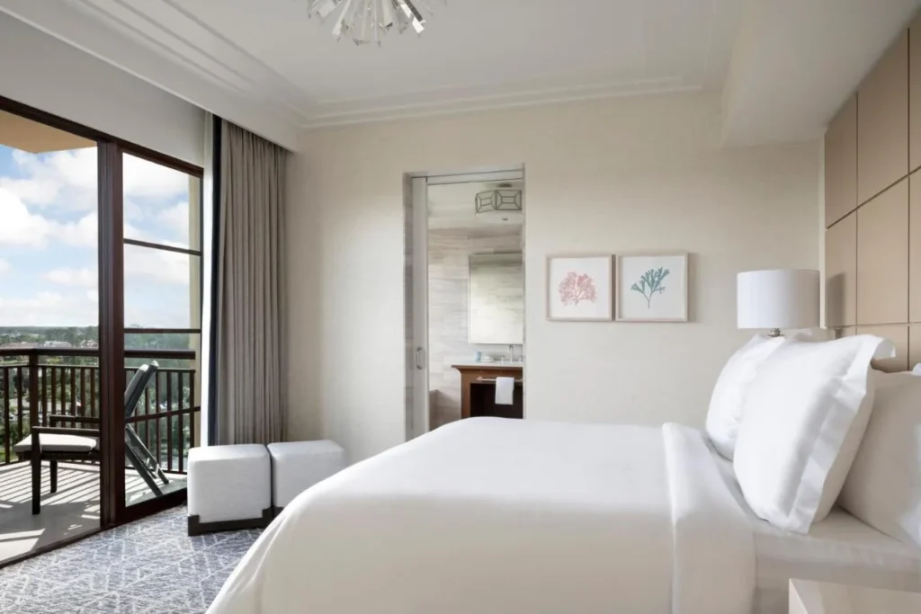 Bedroom with a large bed and a furnished balcony over treetops at Four Seasons Resort Orlando