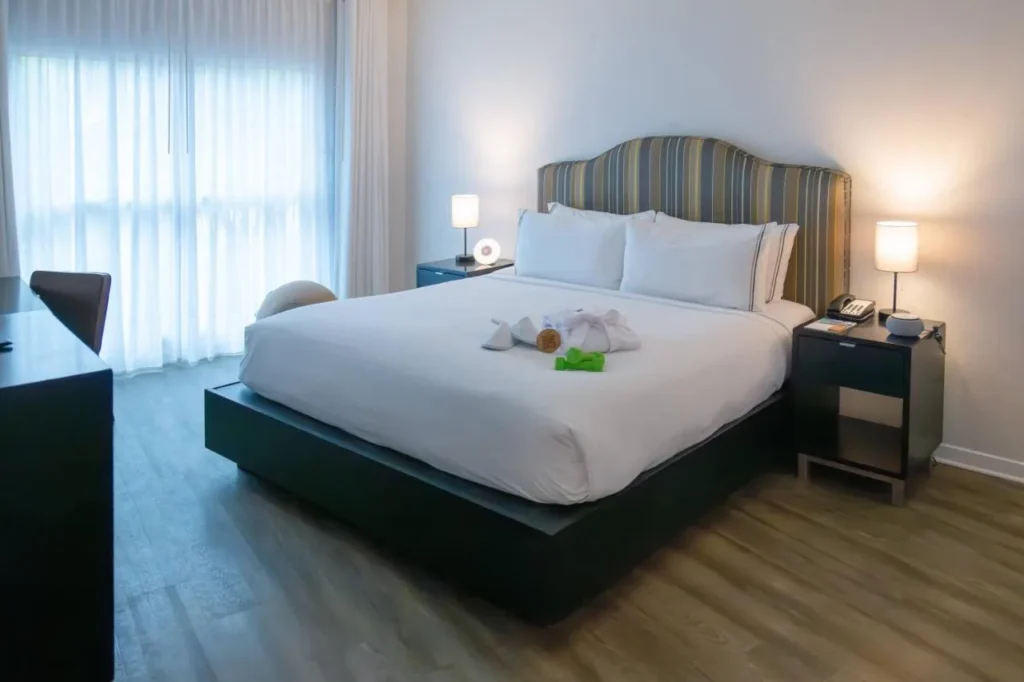 Dormitorio con una cama grande, cabecera a rayas, l&aacute;mparas de noche y cortinas transparentes en Meli&aacute; Orlando Celebration