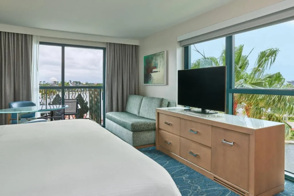 Bedroom with a sofa, TV and lake-view balcony at the Walt Disney World Dolphin