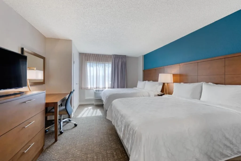 Bedroom with two beds, a desk and a dresser at Staybridge Suites Orlando Royale Parc Suites