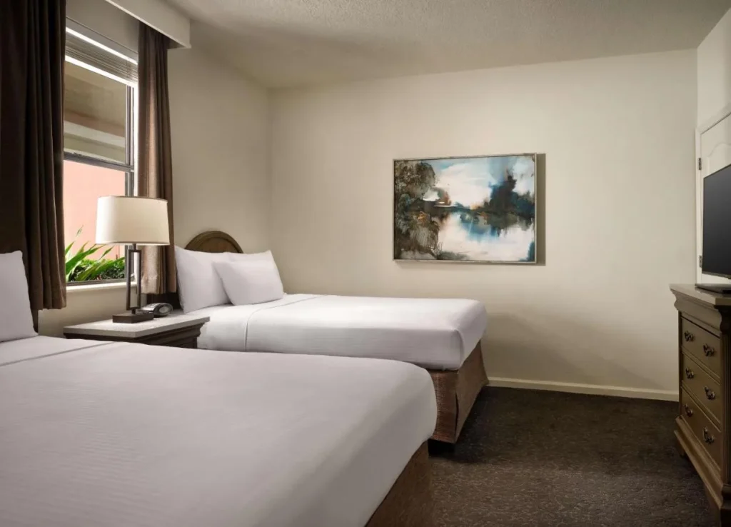 Bedroom with two beds, a dresser and a TV at Caribe Royale Orlando