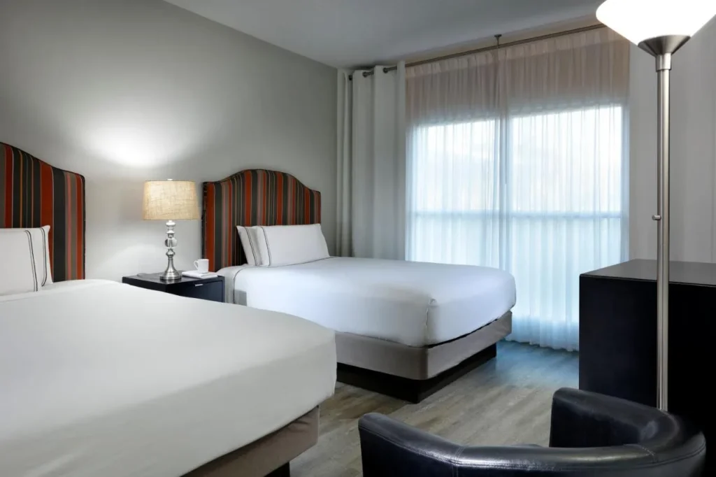 Dormitorio con dos camas, cabeceros a rayas y una ventana con cortinas transparentes en Meliá Orlando Celebration
