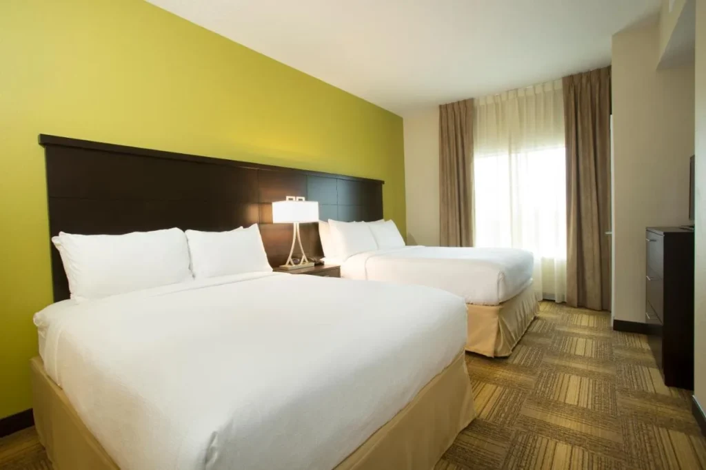 Habitación con dos camas queen y una cómoda en Staybridge Suites Orlando at SeaWorld