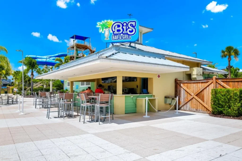 Bis Bar & Grill counter with patio seating and water slides behind at Encore Resort