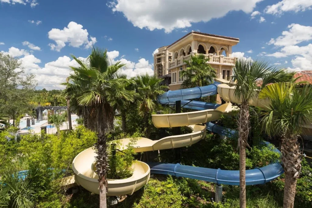 Toboganes de agua azules y beige que serpentean a través de las palmas en Explorer Island, Four Seasons Resort Orlando
