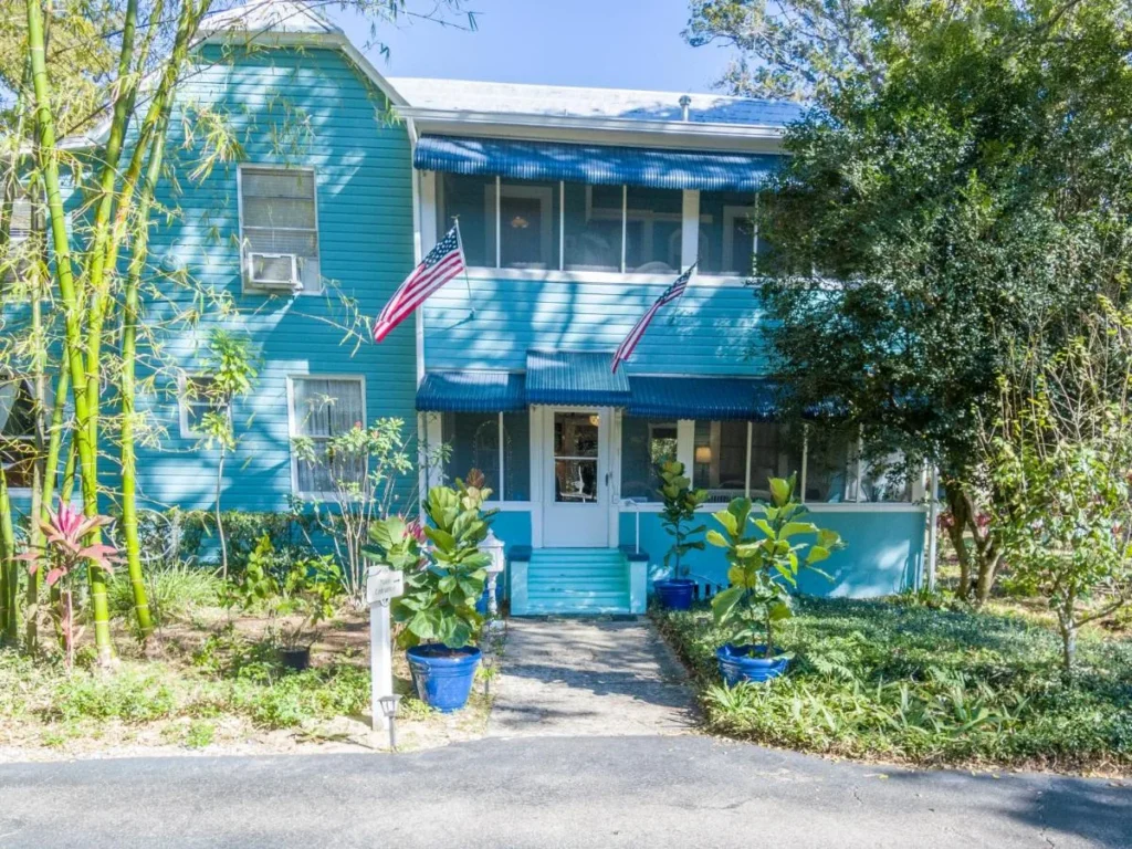 Blue two-story house with screened porches and American flags at The Estate at Mount Dora