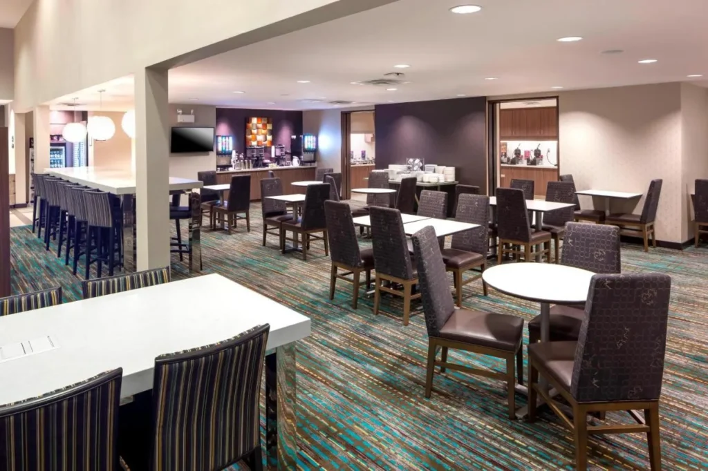 Sala de desayunos con mostradores de buffet, mesas y asientos altos en el Residence Inn Near Universal Orlando