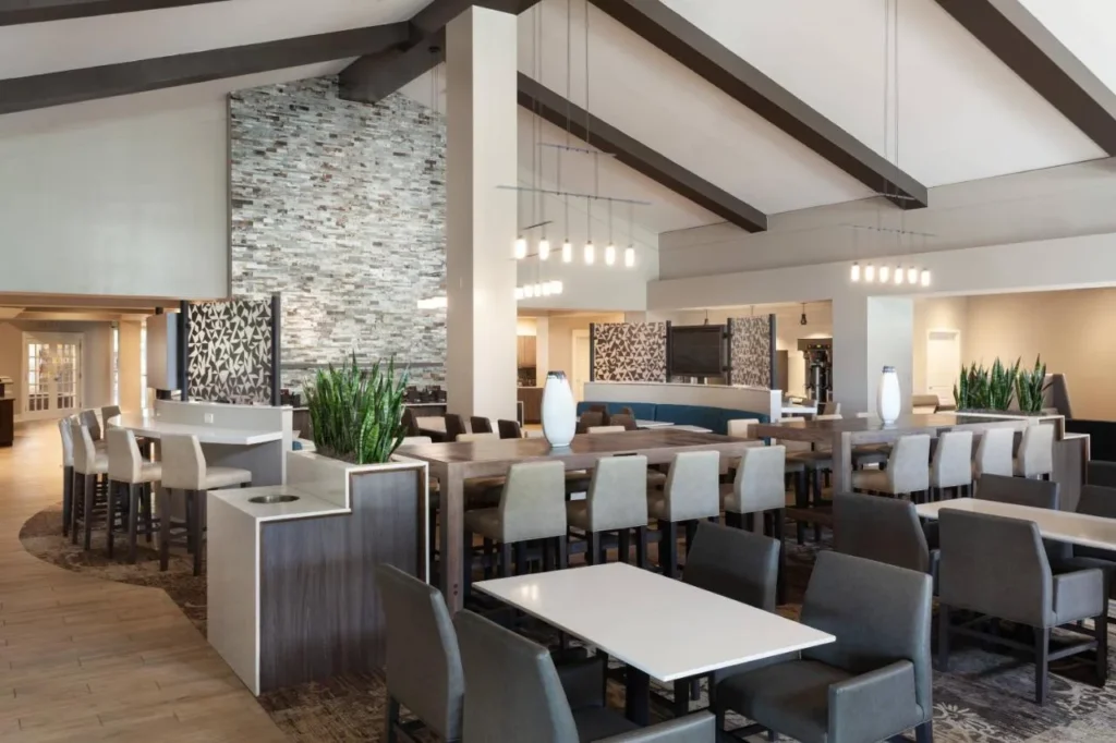 Área de desayuno con mesas comunes, asientos altos y pared de piedra en el Residence Inn Orlando at SeaWorld