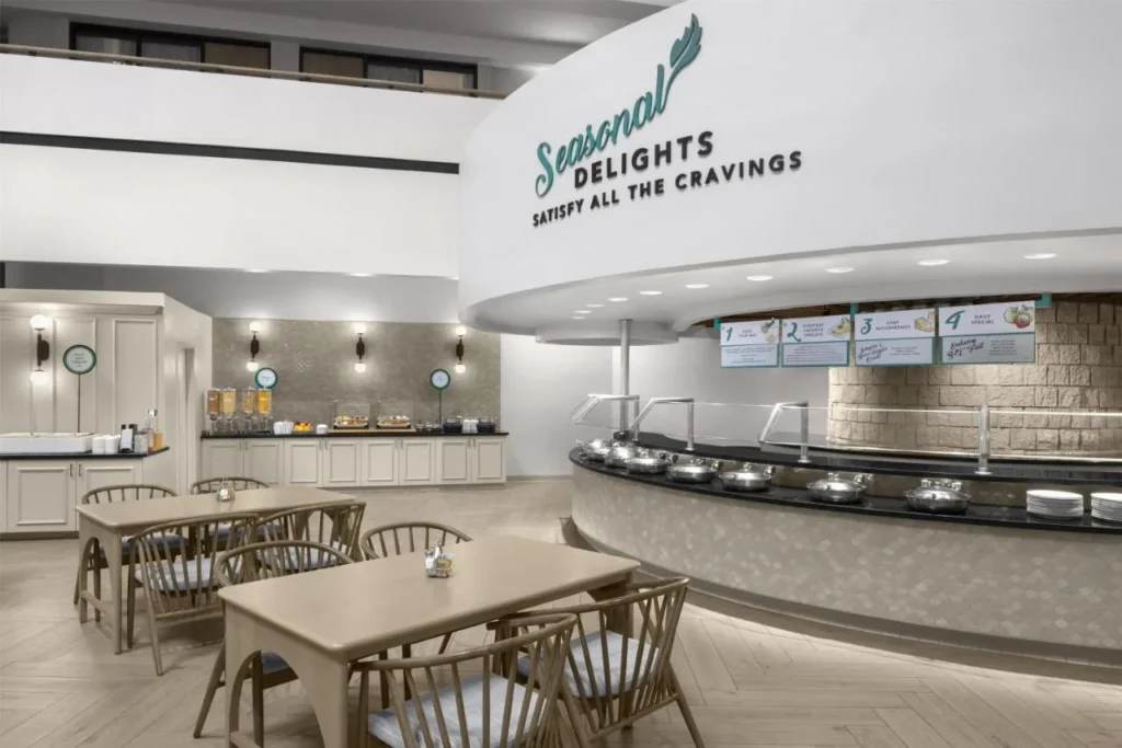 &Aacute;rea de desayuno con estaci&oacute;n de cocina y asientos en el atrio del Embassy Suites ICON Park