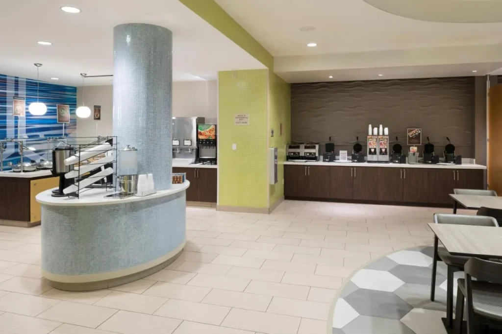 &Aacute;rea de desayuno con fabricantes de gofres y mostrador de comida caliente en SpringHill Suites Orlando SeaWorld