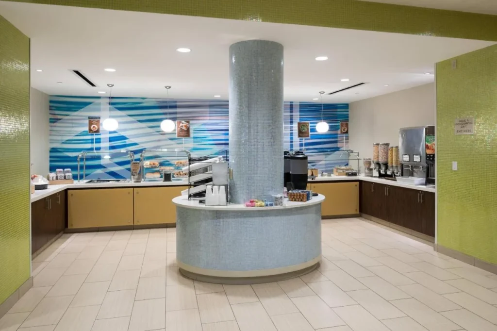 Desayuno buffet con una columna de azulejos y dispensadores de cereales en el SpringHill Suites Orlando at SeaWorld