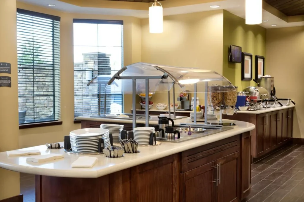 Desayuno buffet con dispensadores de cereales y platos apilados en Staybridge Suites Orlando at SeaWorld