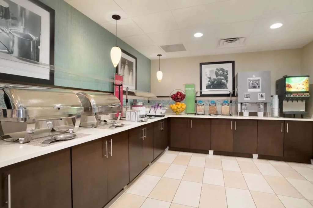 Desayuno buffet en el Hampton Inn Orlando International Drive con platos, frutas y cereales.