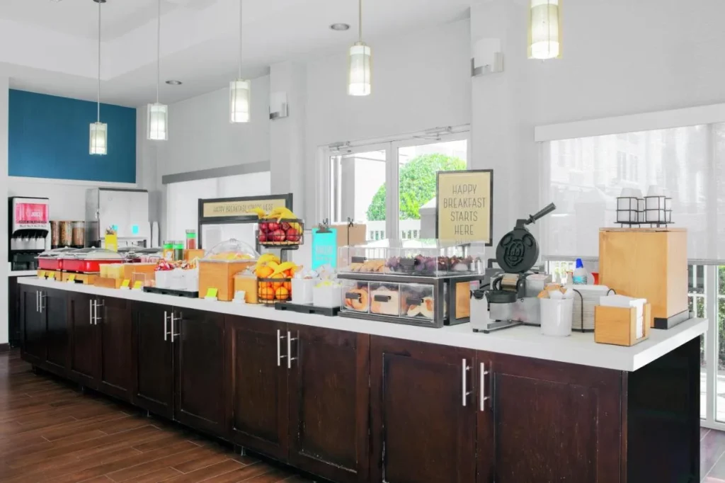 Breakfast buffet counter with Mickey waffle iron, fruit and pastries at Hampton Inn Orlando/Lake Buena Vista