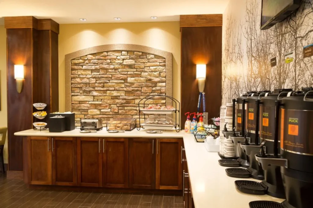 Desayuno estación de café con urnas, tostadora y pared de acento de piedra en Staybridge Suites Orlando at SeaWorld