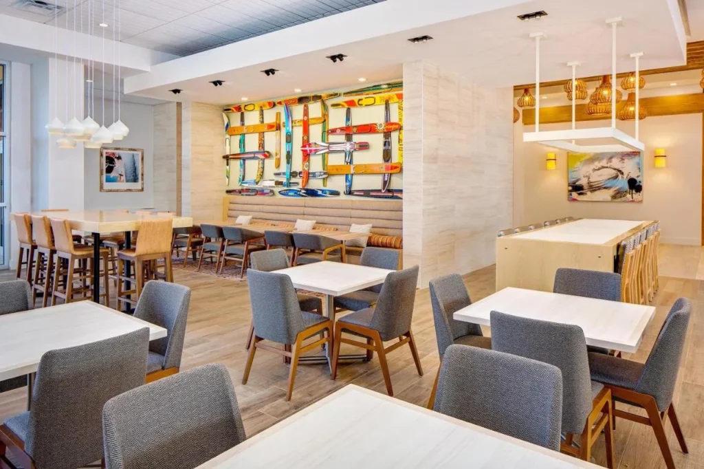 Breakfast dining room with tables and a water-ski wall at Hyatt House across from Universal