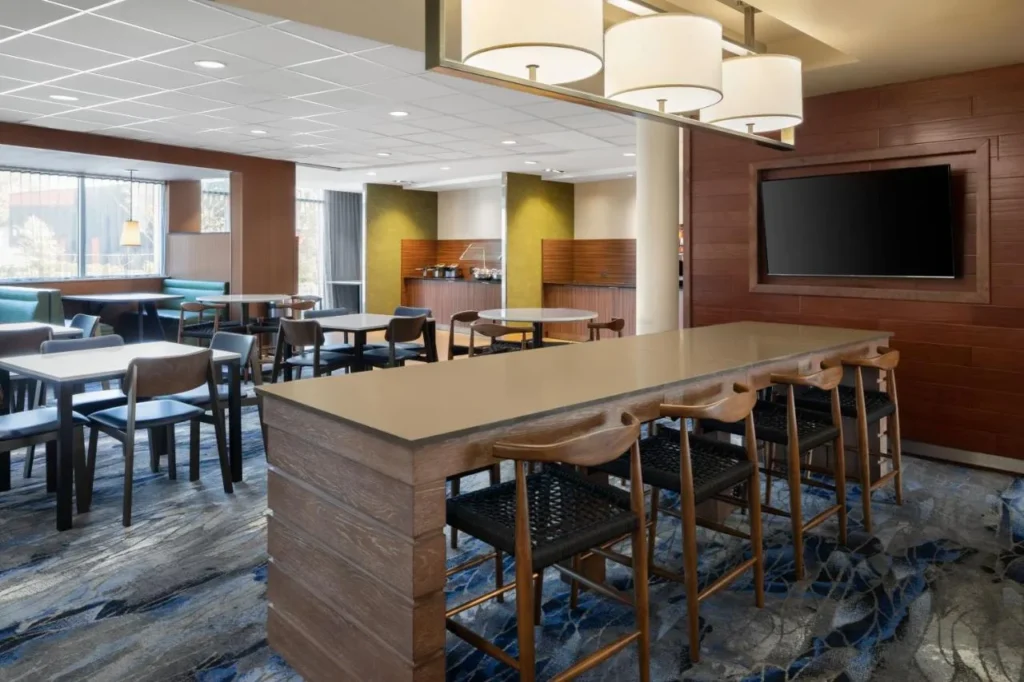 Sala de desayunos con mesa alta, cabinas y TV de pared en Fairfield Inn & Suites Kissimmee/Celebration
