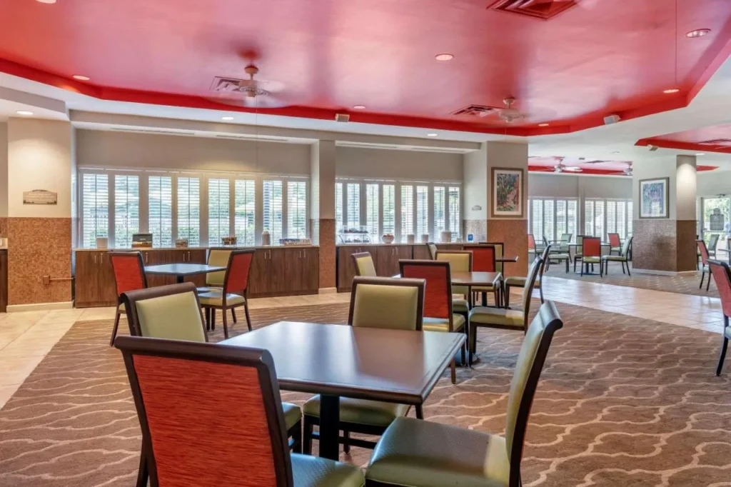 Sala de desayunos con techo rojo y filas de mesas en Comfort Suites Maingate East