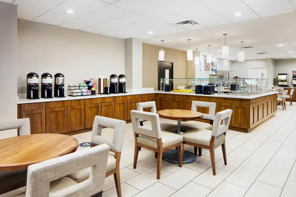 Breakfast room with round tables, coffee station and buffet counter at Staybridge Suites Royale Parc