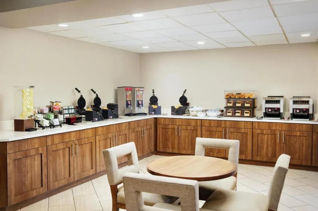 Sala de desayunos con wafleras, tostadoras y una mesa redonda en Staybridge Suites Royale Parc