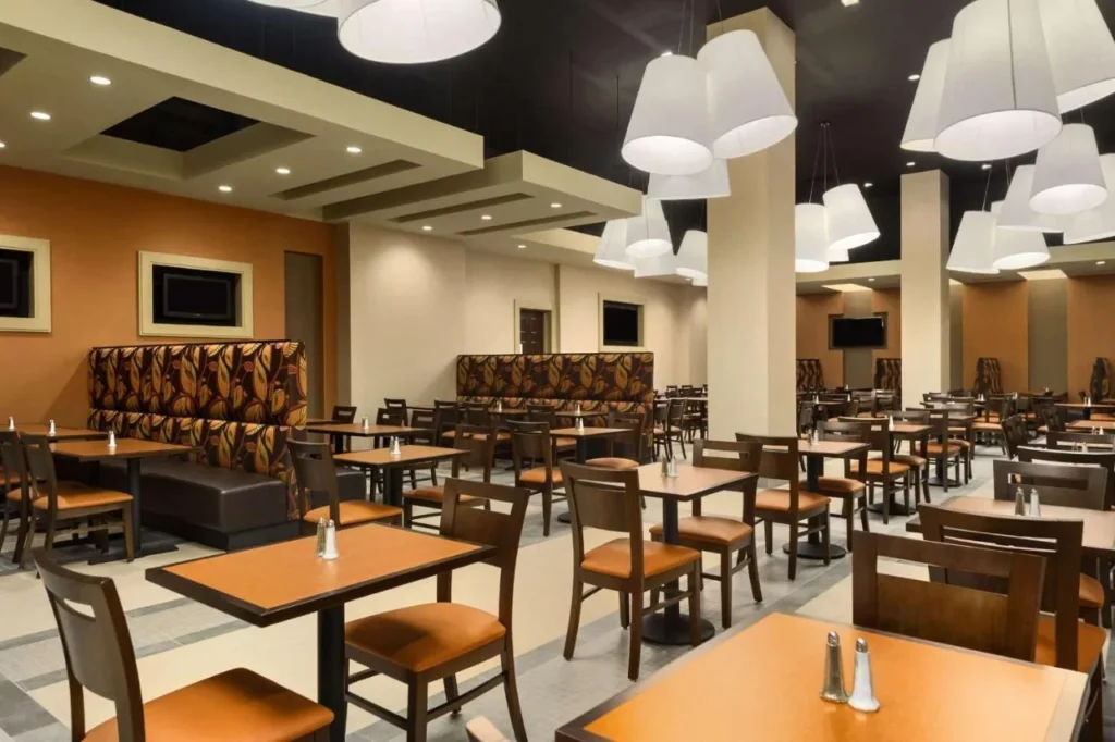 &Aacute;rea para desayunar con cabinas y luces colgantes en Embassy Suites Lake Buena Vista South