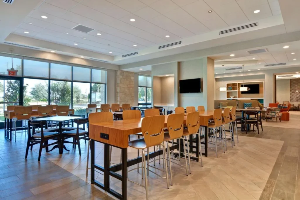 Área de asientos para el desayuno con mesas y sillas altas de madera en Home2 Suites Flamingo Crossings
