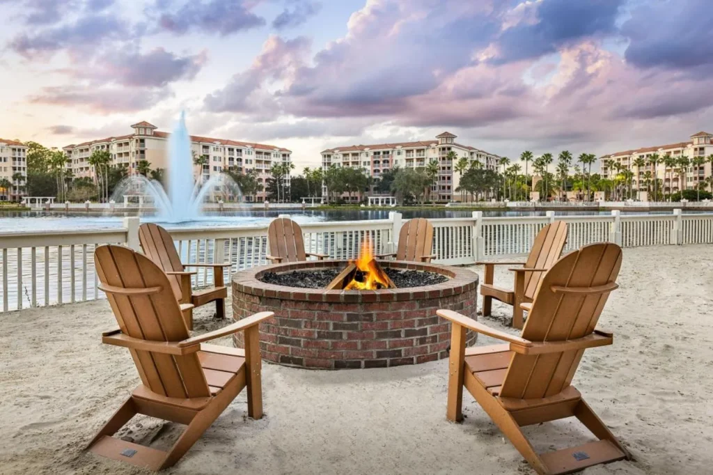 Hoyo de fuego de ladrillo con sillas Adirondack en la playa arenosa junto al lago en Marriott's Grande Vista