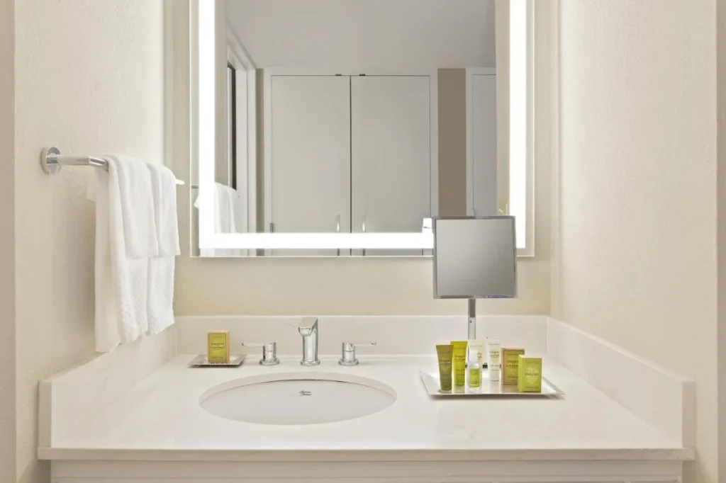 Vanidad de baño brillante con espejo iluminado y artículos de aseo en Hilton Orlando Lake Buena Vista
