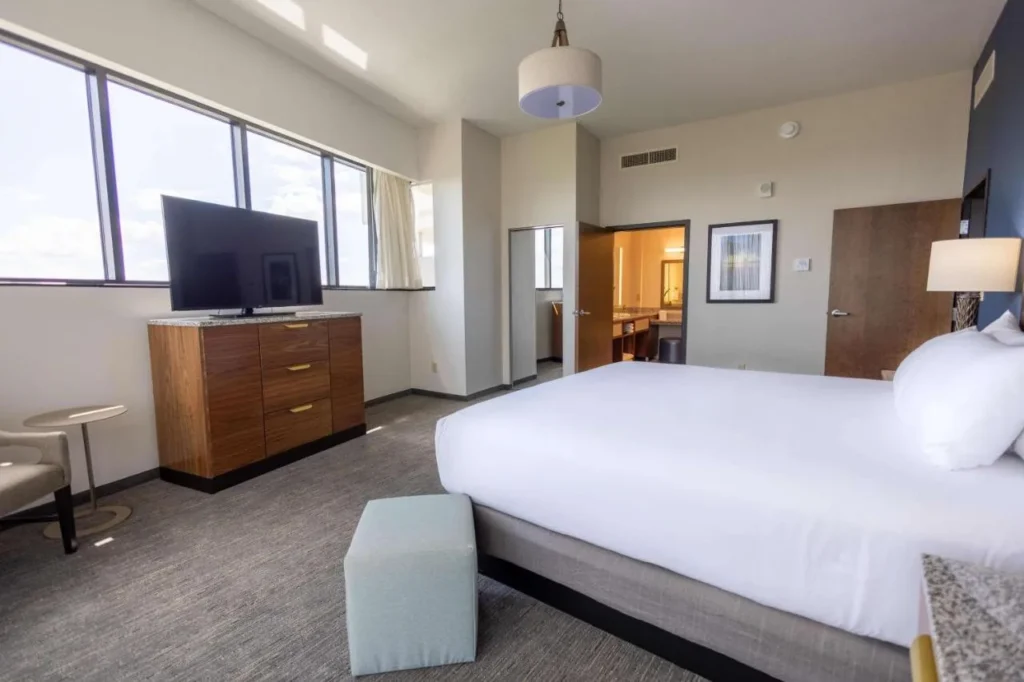 Bright bedroom with wide windows and a TV dresser at Drury Plaza Hotel Orlando