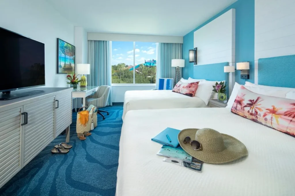 Bright guest room with two queen beds and a window view at Loews Sapphire Falls Resort