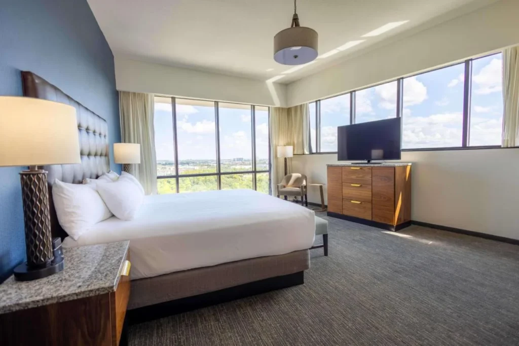 Bright king room with floor-to-ceiling corner windows and a TV dresser at Drury Plaza Hotel Orlando