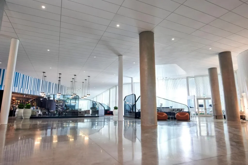 Luminoso vest&iacute;bulo en el Universal Aventura Hotel con pisos pulidos, columnas de concreto y sillones naranjas