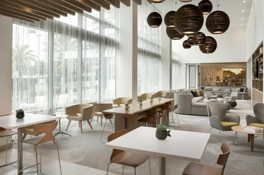 Bright lobby dining area with high windows and communal tables at Element Orlando Universal Blvd.