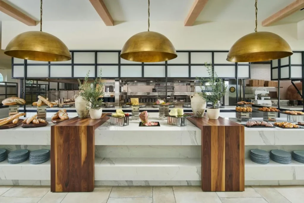 Contador buffet con panes, pasteles y quesos bajo lámparas colgantes de latón en Gaylord Palms Resort