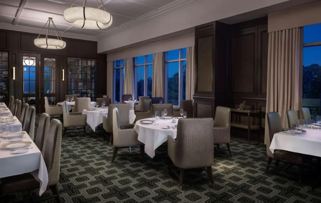 Comedor asador Bull & Bear con manteles blancos y ventanas altas en Waldorf Astoria Orlando