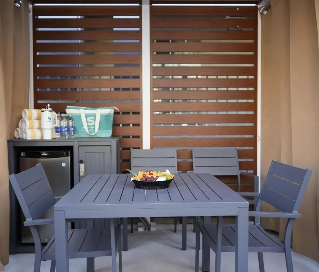 Caba&ntilde;a con mesa, mini nevera, toallas y plato de frutas en Holiday Inn Resort Orlando Suites