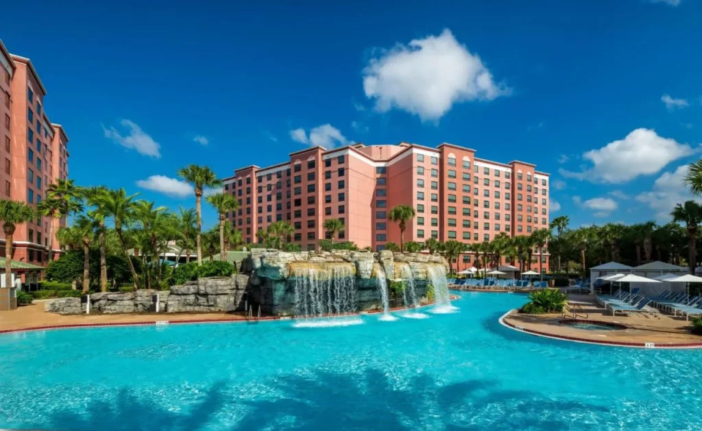 Caribe Royale Orlando piscina principal con cascadas de roca, caba&ntilde;as, palmeras y torres de hotel
