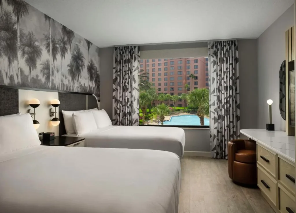 Caribe Royale Orlando room with two beds, palm mural wall and a window facing the pool