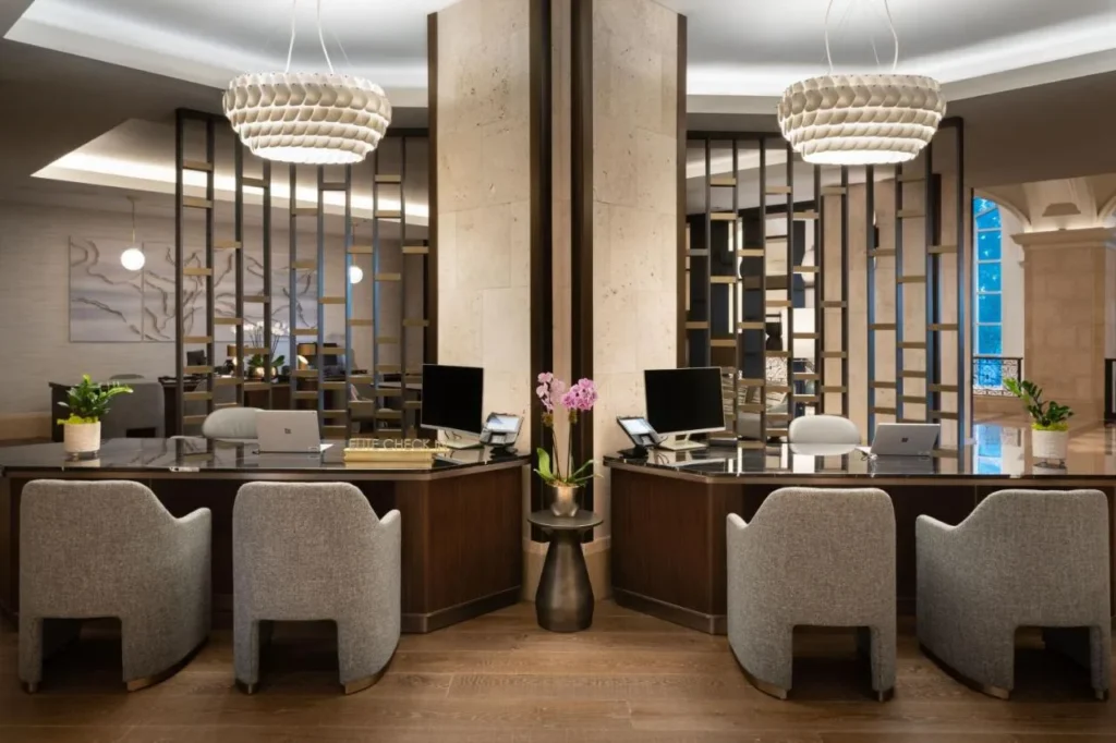 Mesas de check-in con sillones grises y luces colgantes en JW Marriott Orlando Grande Lakes